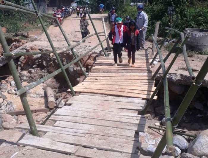 Phụ huynh lo lắng về độ an toàn của cầu tạm nên dẫn các em qua suối rồi mới trở về đi làm. Ảnh: LAL
