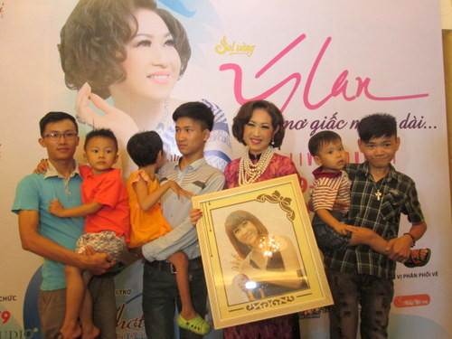 Ý Lan cùng các em nhỏ trong mái ấm Bác Ái và bức tranh do các em tặng.