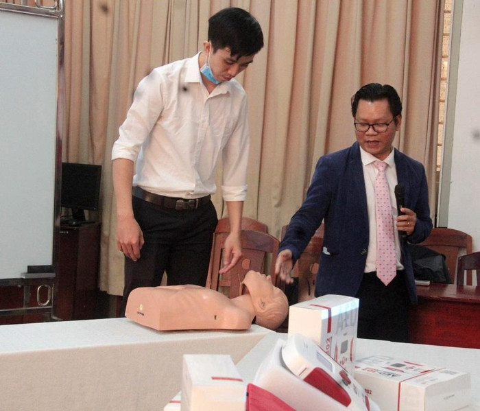 Thạc sĩ Lê Văn Chung cùng nhóm nghiên cứu chia sẻ về công năng của máy AED-302 Trainer dùng trong huấn luyện sơ cấp cứu đột quỵ. Ảnh: AN