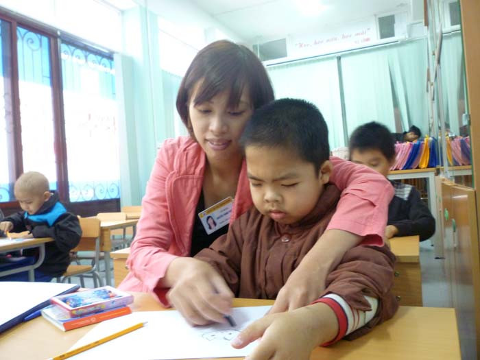 Em bé này chưa một ngày được đi học, tay vẫn còn đau vì truyền dịch. Em không thể cầm bút vẽ như các bạn nhưng vẫn cố gắng, kiên trì, khéo léo theo từng nét bút của cô Phượng. (Ảnh Thu Hòe)