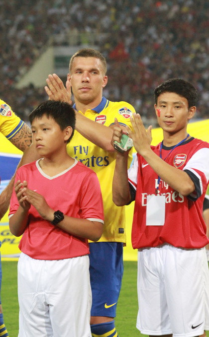 Vũ Xuân Tiến dẫn đầu khi hai đội bước ra sân và đứng cạnh Podolski. Ảnh: Infonet