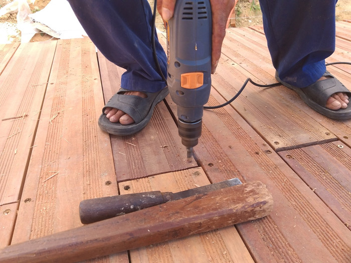 Để thi con đường, đơn vị thi công sẽ đỗ cầu bằng bê tông sau đó đóng ván gỗ lim xuống và gia cố bằng đinh vít. Trong hình công nhân đang khoan đóng dấu gỗ xuống nền bê tông. Để thi con đường, đơn vị thi công sẽ đỗ cầu bằng bê tông sau đó đóng ván gỗ lim xuống và gia cố bằng đinh vít. Trong hình công nhân đang khoan đóng dấu gỗ xuống nền bê tông.