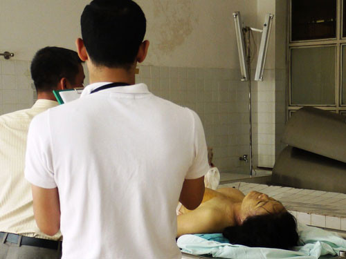 Cơ quan chức năng làm thủ tục giám định pháp y tử thi bà Mai, với sự chứng kiến của anh Khanh (phải)