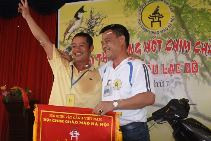 Ông Nguyễn Quốc Toản (bên phải) trao phần thưởng cho một hội viên trong lần thi chim chào mào tại Hà Nội