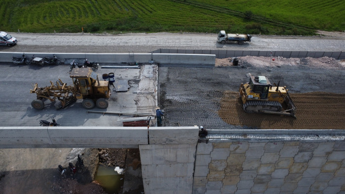 Các công nhân đang thực hiện việc đầm nền tại vị trí máy ủi và xe lu không tiếp cận được. Ảnh: T.D