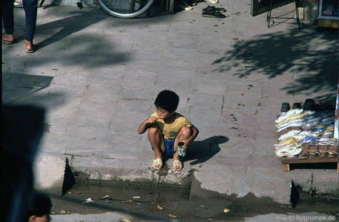 Một cậu bé ngồi đánh răng bên ven đường. Một cậu bé ngồi đánh răng bên ven đường.