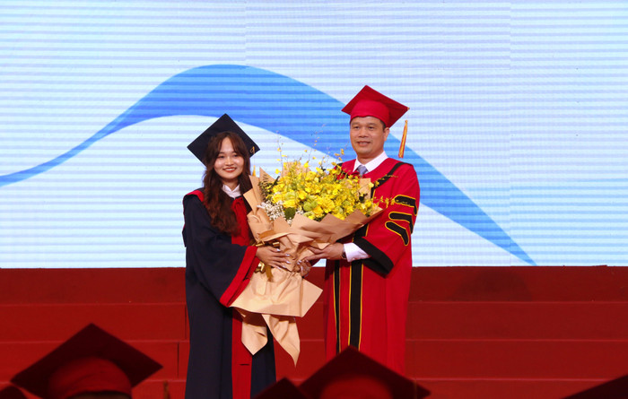 Sinh viên Phạm Trúc Quỳnh thay mặt gần 6.000 tân tiến sĩ, thạc sĩ, kỹ sư và cử nhân tặng hoa tri ân nhà trường. GDVN_tang hoa.JPG