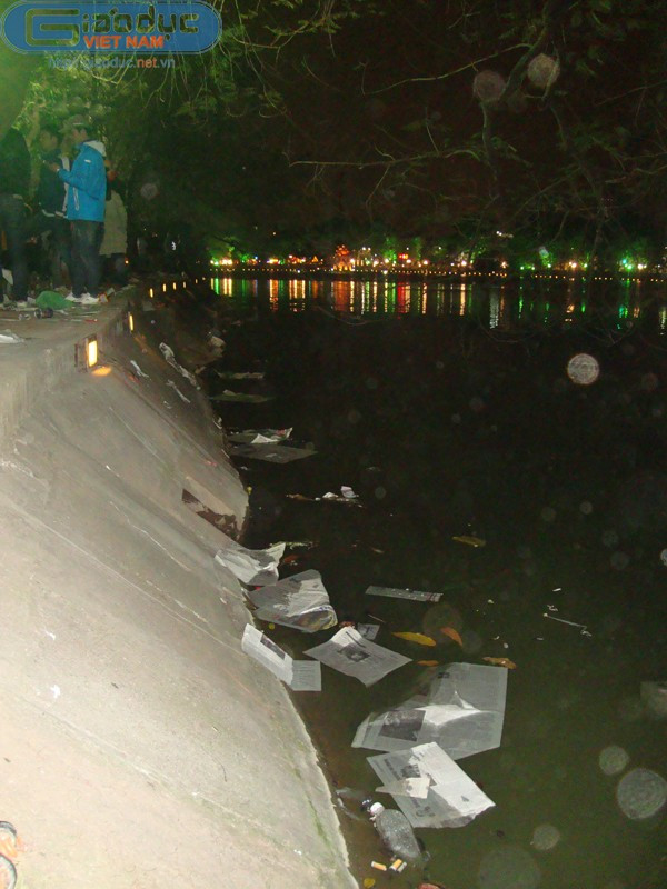 Những tờ báo hút theo gió và bước chân người đi bay xuống hồ.