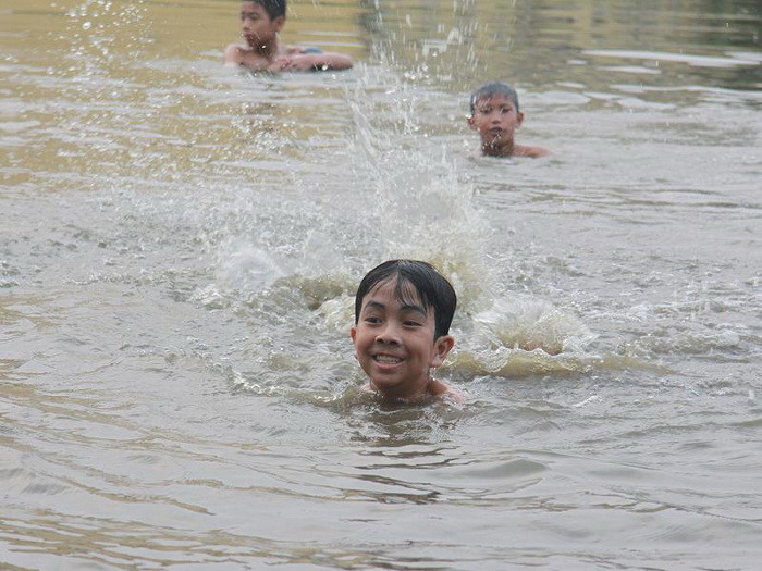 Cậu bé này hồn nhiên vui vẻ vẫy vùng giữa dòng nước giữa trời hè nóng bức.