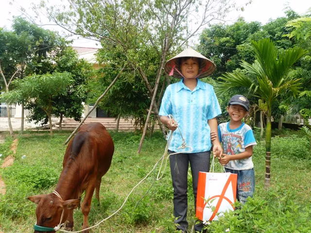 Em Ôn Văn Tĩnh (phải) cùng mẹ vui mừng vì được các nhà hảo tâm hỗ trợ mua được con bò để gây vốn.