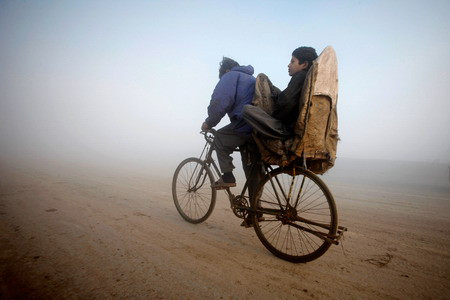 Một cậu bé ngồi sau chiếc xe đạp trong buổi sáng sương giá ở Lahore, Pakistan. Một cậu bé ngồi sau chiếc xe đạp trong buổi sáng sương giá ở Lahore, Pakistan.