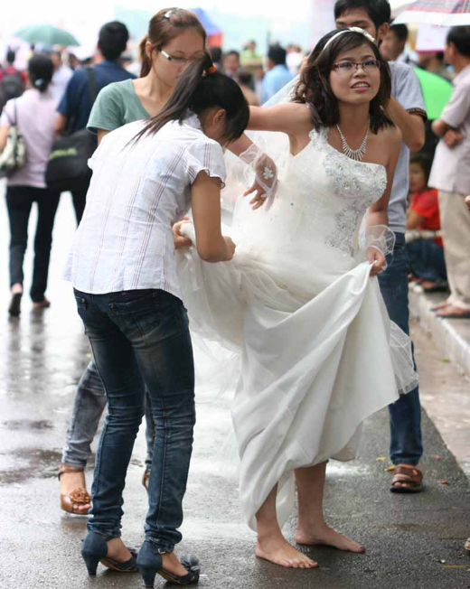 …còn cô dâu thì buộc váy lên cao, bỏ giày cao gót. Ảnh: Sài gòn tiếp thị …còn cô dâu thì buộc váy lên cao, bỏ giày cao gót. Ảnh: Sài gòn tiếp thị