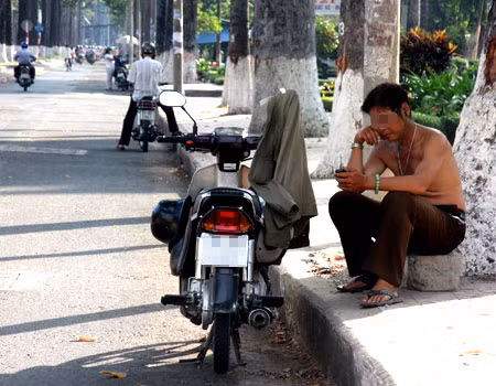 Người đàn ông này phải cởi áo ngồi dưới gốc cây trên đường Ngô Gia Tự, quận 5, để nghỉ ngơi. Ảnh: VnExpress