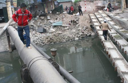 Nhiều người tìm lối đi khác, men theo một đường ống qua sông.