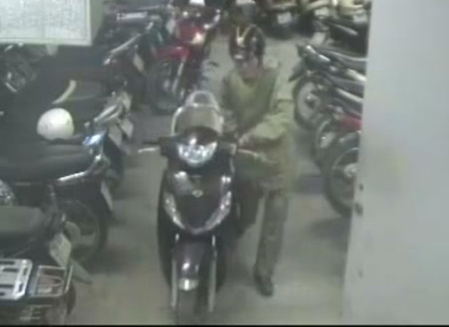 Người đàn ông mặc áo mưa dắt chiếc SH ra khỏi hầm.