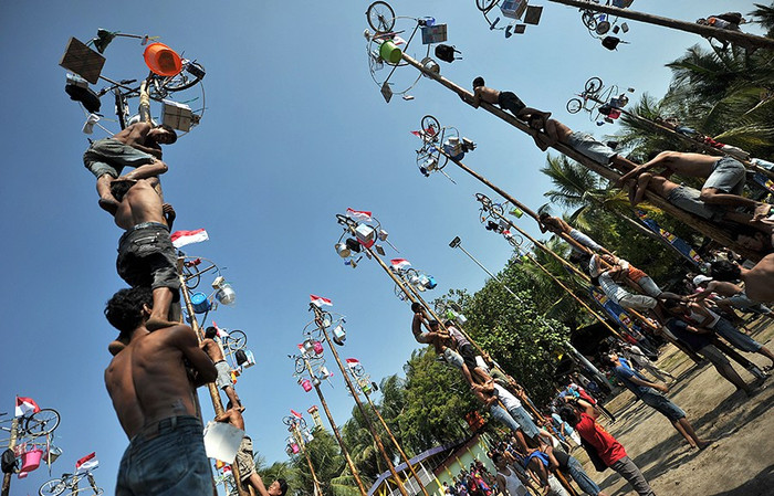 Những cột gỗ cao nhẵn bóng được chôn thẳng đứng, đỉnh cột treo cờ và giải thưởng hấp dẫn Những cột gỗ cao nhẵn bóng được chôn thẳng đứng, đỉnh cột treo cờ và giải thưởng hấp dẫn