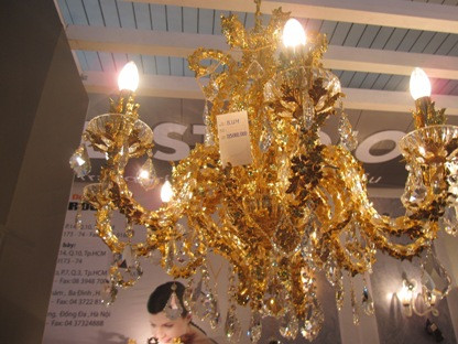 Với đèn chùm “HORSE”, các con ngựa màu đỏ được đúc từ pha lê Séc nguyên khối, các cánh dưới đèn được làm từ đồng mạ vàng 24k, ngoài ra trên sản phẩm còn được đính các hạt pha lê cao cấp Swarovski của Áo. Giá bán của sản phẩm 1,647 tỷ đồng. Còn đèn “BLUM” có 2 mẫu thiết kế gồm đèn để bàn và đèn chùm treo trên trần nhà. Sản phẩm này cũng được mạ vàng 24k, nhưng các hạt Swarovski không phải màu đỏ mà là màu trắng. Ảnh: Đèn "BLUM" treo trần giá 735 triệu đồng