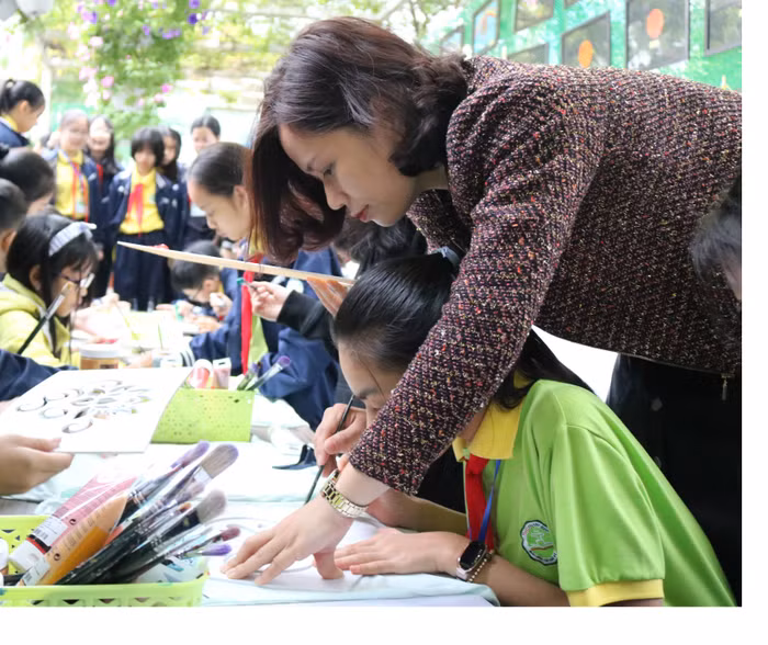 Cô Thạch Thị Thanh Quyên - Chủ nhiệm câu lạc bộ nghệ thuật hướng dẫn các học sinh trải nghiệm sáng tạo nghệ thuật tại gian hàng. Ảnh: Đỗ Thơm