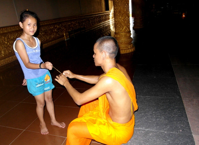 Vị sư trẻ đang buộc dây chỉ cầu may mắn cho một cô bé. Vị sư trẻ đang buộc dây chỉ cầu may mắn cho một cô bé.