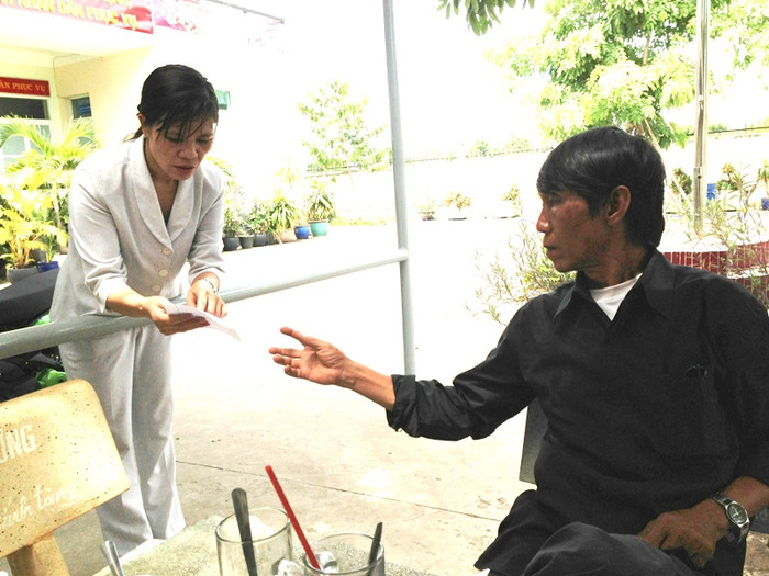 Ông Lê Đình Phú đang nhận lá đơn viết tay của bà Phạm Thị Bình, tố cáo chính vợ ông, người gây ra vụ đánh ghen kinh hoàng, chuẩn bị chạy đi đánh máy giúp.Ảnh: Dương Cầm