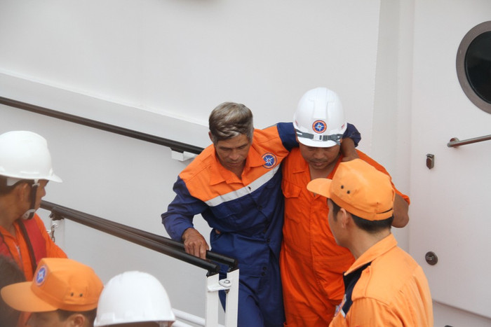 Các thuyền viên tàu SAR 412 dìu từng ngư dân bị nạn trên tàu cá lên bờ trong ánh mắt ngóng trông của người thân....