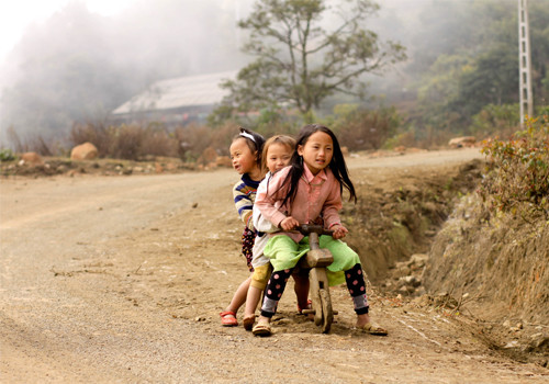 Những em bé Tây Bắc hồn nhiên trên chiếc xe đạp gỗ.