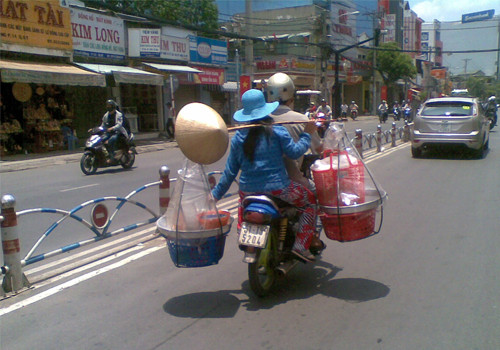 Ngồi xe máy vẫn gánh hàng. Ảnh: Đình Chí. Ngồi xe máy vẫn gánh hàng. Ảnh: Đình Chí.