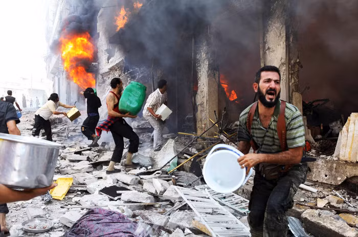 Những người dân Syria dập lửa tòa nhà trúng đạn của quân chính phủ hôm 4/9 làm 4 người tử vong