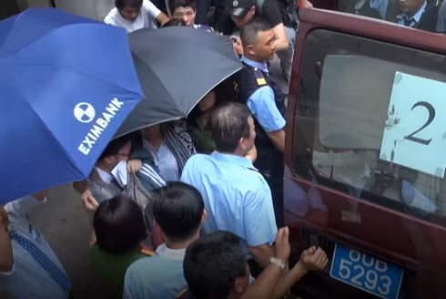 Nhân viên ngân hàng Eximbank bị bắt giữ, áp giải ra xe để về nơi tạm giam. (Ảnh: H.L)