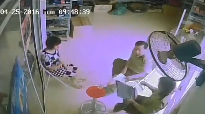 Một nam cán bộ quản lý thị trường cầm tờ giấy, nghi có kẹp vật giống tiền để đưa cho nữ cán bộ (ảnh cắt từ clip).