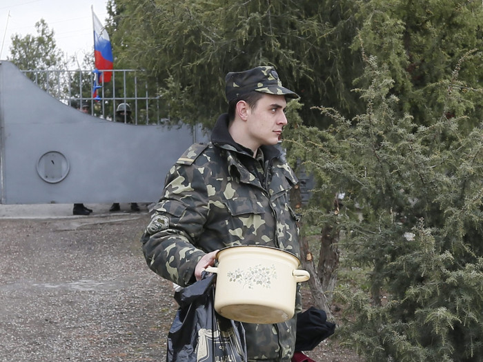 Một người lính Ukraine rời căn cứ quân sự tại Sevastopol, Crimea cùng đồ đạc cá nhân khi cờ Nga đã kéo lên bên trong cơ sở này.