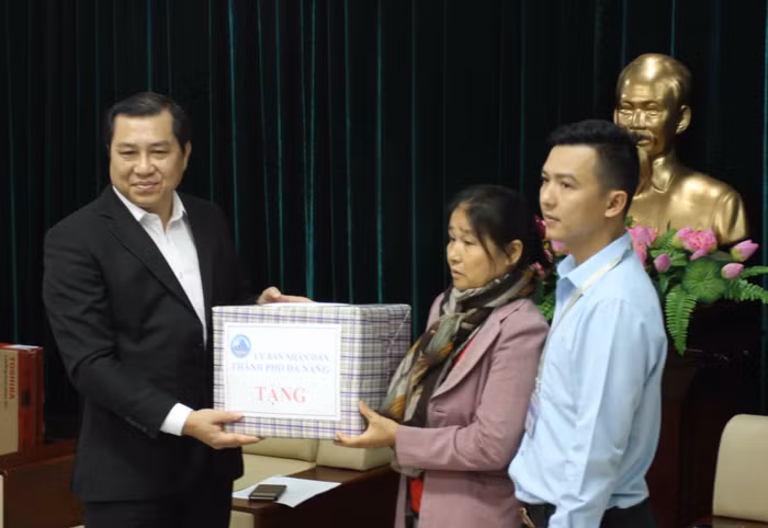 Ông Huỳnh Đức Thơ, Chủ tịch UBND TP Đà Nẵng trao quà và quyết định bố trí căn hộ chung cư cho bà quả phụ Nguyễn Thị Tần, vợ Liệt sĩ Vũ Phi Trừ và con trai là Vũ Xuân Khoa vào sáng 12/3. Ảnh: Thùy Linh