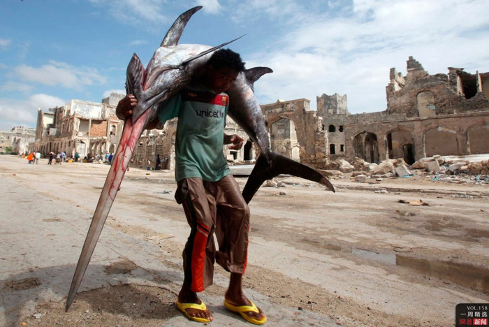 Ngày 18 tháng 12, tại Mogadishu, Somalia, một thanh niên vác con cá kiếm vừa bắt ra chợbans Ngày 18 tháng 12, tại Mogadishu, Somalia, một thanh niên vác con cá kiếm vừa bắt ra chợbans