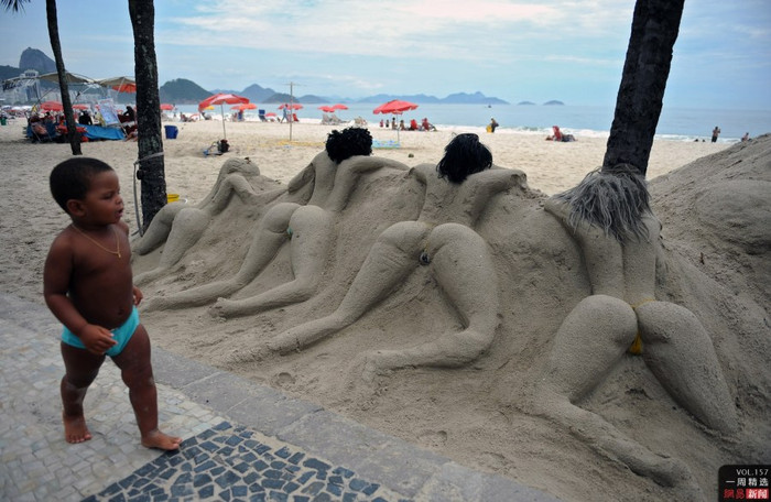 Một cậu bé ở Rio de Janeiro, Brazil đi qua tác phẩm tạo hình bằng cát trên bãi biển Một cậu bé ở Rio de Janeiro, Brazil đi qua tác phẩm tạo hình bằng cát trên bãi biển