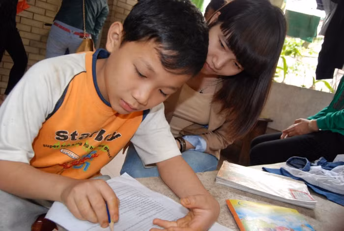 Gia sư hướng dẫn trẻ em trong làng trẻ SOS học bài.