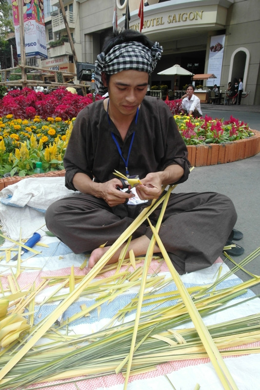 Áo bà ba nâu, khăn rằn, chàng trai quê này đang tết lá dừa thành những món đồ chơi cho trẻ nhỏ. Áo bà ba nâu, khăn rằn, chàng trai quê này đang tết lá dừa thành những món đồ chơi cho trẻ nhỏ.