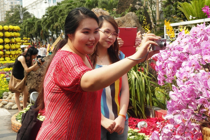 Hai cô gái thích thú chụp ảnh hoa lan tím. Hai cô gái thích thú chụp ảnh hoa lan tím.