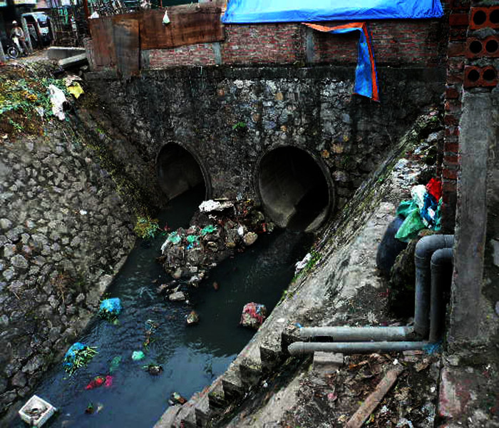 Phía sau xóm là chợ đầu mối hoa quả Long Biên ồn ào, nồng nặc mùi hoa quả thối, phía trước mặt là cống to ngập ngụa rác và nước thải đen kịt. Phía sau xóm là chợ đầu mối hoa quả Long Biên ồn ào, nồng nặc mùi hoa quả thối, phía trước mặt là cống to ngập ngụa rác và nước thải đen kịt.