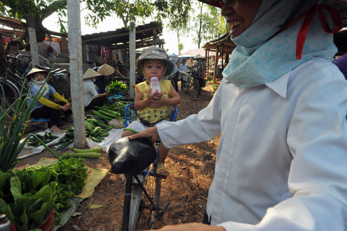 Em bé ngồi trên xe đạp theo mẹ đi chợ mua hàng. Em bé ngồi trên xe đạp theo mẹ đi chợ mua hàng.