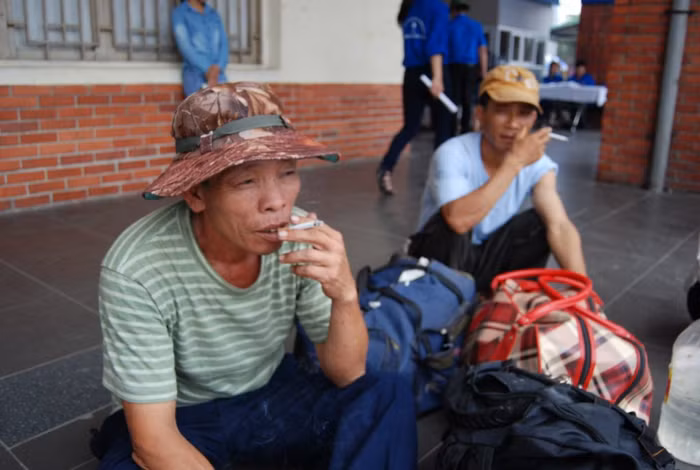 Một phụ huynh ngồi nghỉ tại bến xe sau một chặng đường dài