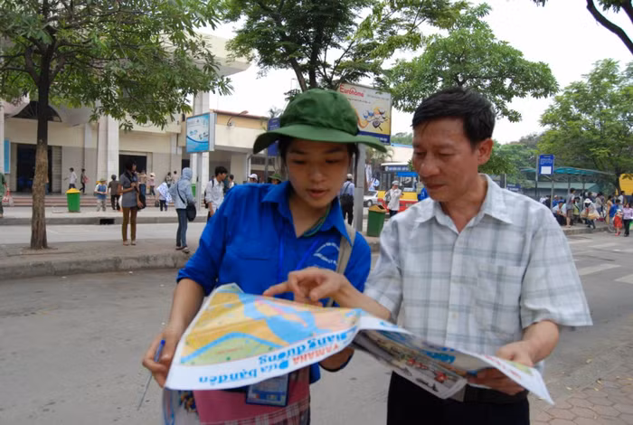 Sinh viên tình nguyện hướng dẫn đường đi tại bến xe bus cho phụ huynh.