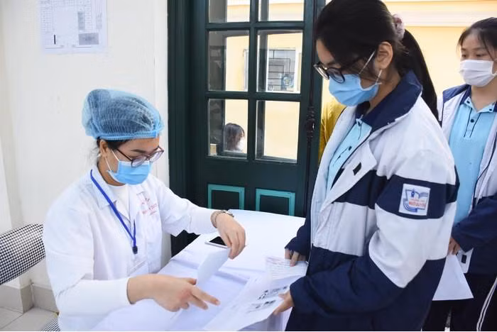 Nhân viên y tế kiểm tra danh sách học sinh đăng ký tiêm (Ảnh: NH)