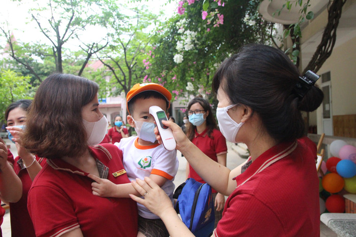 Các cô đón trẻ và kiểm tra thân nhiệt khi học sinh quay trở lại trường sau đợt nghỉ dịch Covid-19. Ảnh nhà trường cung cấp