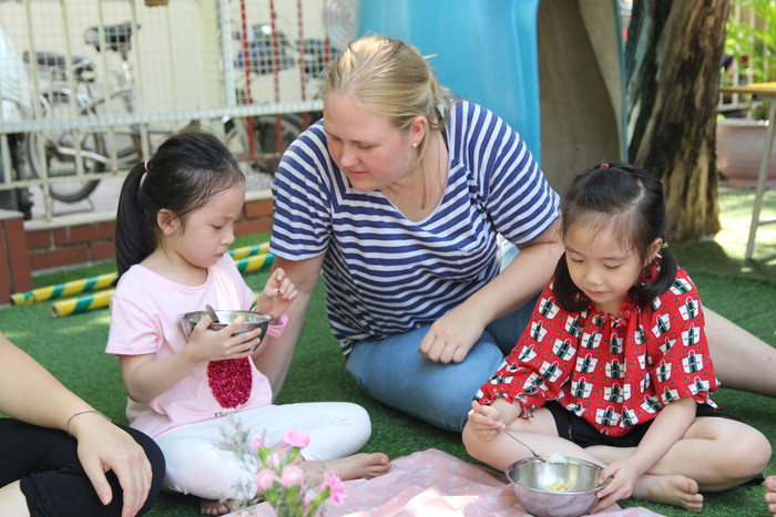 Sau khi ra sân thấy thời tiết rất đẹp, cô trò bàn nhau xin bác Hiệu trưởng được ăn trưa ngoài sân. Ảnh: Nhà trường cung cấp