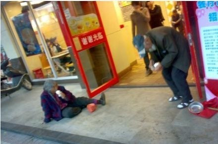 Hai ông bà già xin ăn trước một cửa hàng