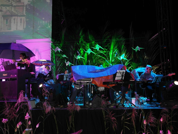 Các nhạc công đánh đàn dưới cơn mưa càng lúc càng nặng hạt. Ảnh: Dương Cầm