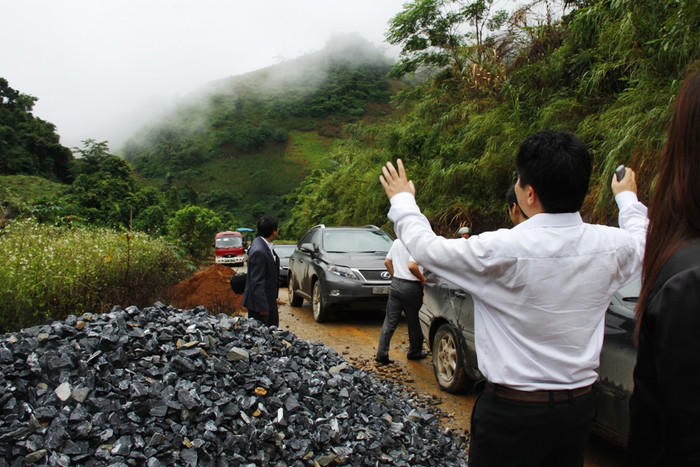 Một thành viên trong đoàn xung phong làm “cảnh sát giao thông” điều hành đoàn xe đi qua bãi đá.