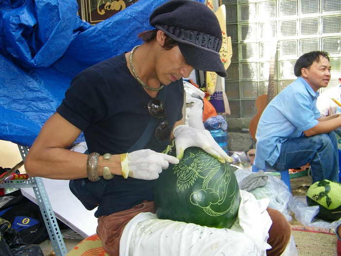 Nghệ nhân Tony đang khắc thư pháp trên quả dưa hấu. Mỗi trái dưa sau khi khắc chữ, hoa văn sẽ được bán với giá 300.000 đồng.