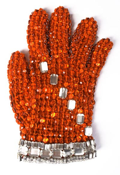 Găng tay được may từ vải spandex gắn hạt Swarovski Loch Rosen màu cam và các hạt pha lê trắng vuông. Trị giá của đôi găng này khoảng 1000 - 1500 USD. Găng tay được may từ vải spandex gắn hạt Swarovski Loch Rosen màu cam và các hạt pha lê trắng vuông. Trị giá của đôi găng này khoảng 1000 - 1500 USD.