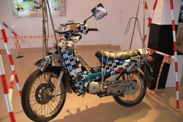 Một xe máy bị hư hỏng sau tai nạn giao thông. Trên xe máy này có gắn số những biển số các tỉnh, thành bị tai nạn giao thông. Ở phía gương chiếu hậu xe máy, có hình ảnh một em bé đang quấn vành trắng khăn tang... Một xe máy bị hư hỏng sau tai nạn giao thông. Trên xe máy này có gắn số những biển số các tỉnh, thành bị tai nạn giao thông. Ở phía gương chiếu hậu xe máy, có hình ảnh một em bé đang quấn vành trắng khăn tang...